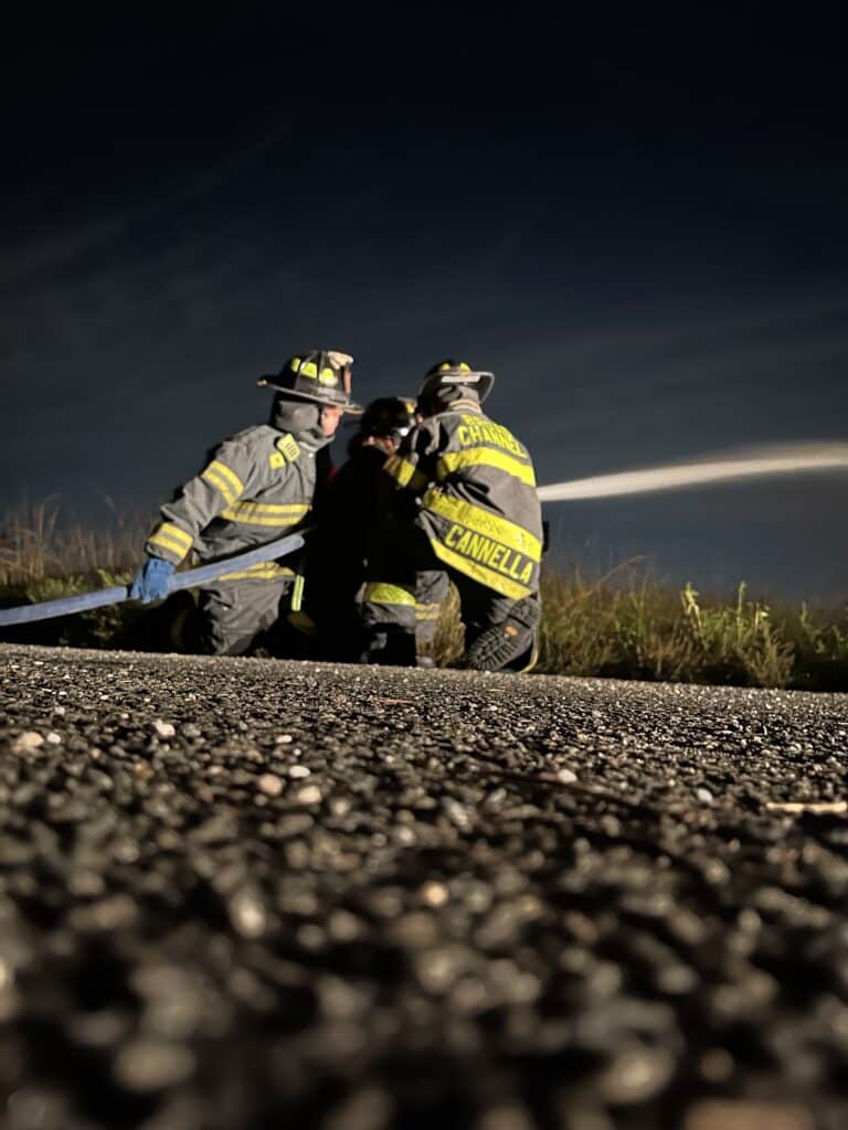 looking up at three firefighters using a hose